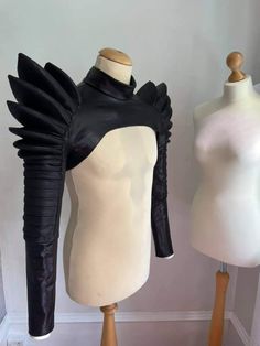 two mannequins with black leather wings on them