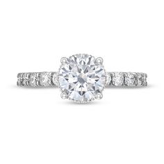 a diamond engagement ring with two side stones on the band and an oval center stone