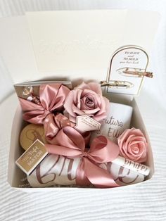 an open box filled with lots of pretty pink flowers next to a notepad and pen