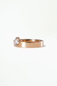 a gold ring with a single diamond on the top, against a white background that appears to be part of a wedding band