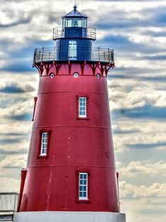 a red and white lighthouse under a cloudy sky