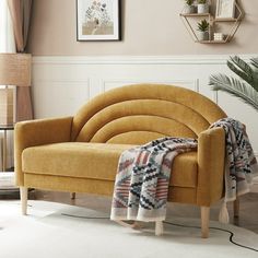 a living room scene with focus on the couch and rug in the foreground, there is a potted plant next to it