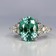 🐕 Big deals! Oval cut teal green tourmaline ring 14K solid gold paraiba tourmaline engagement ring Unique vintage moissanite wedding ring for women #7326 only at $828.00 Hurry. #CustomRing #ParaibaTourmaline #ModernRing #WeddingRing #HandmadeJewelry #ClusterRing #MoissaniteDiamond #AlternativeRing #OvalCutShaped #EngagementRing Elegant Green Oval Topaz Ring, Oval Moissanite Emerald Green Ring, Oval Green Moissanite Emerald Ring, Oval Emerald Moissanite Ring, Elegant Green Aquamarine Rings, Green Oval Topaz Ring For Wedding, Green Aquamarine Ring With Center Stone, Oval Emerald Ring With Moissanite And Accent Stones, Paraiba Tourmaline Engagement Ring