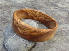 handmade Bracelet Bangle made out of fine olive wood Diameter inside 6,5 cm ( 2,56 inch) large 2 cm ( 0,79 inch) the olive wood is finely sanded and oiled with olive oil naturally the grain of the olive wood can vary from item to item , but in any case you will get a olive wood bracelet with beautiful grain This bangles are turned by us from a piece of olive wood. Handmade in Portugal In our Shop you can find more earrings , rings and necklaces made out of olive wood ! Handmade Natural Color Bangle Bracelets, Handmade Natural Color Bangle Bracelet, Earthy Natural Wood Jewelry For Gifts, Bohemian Wood Bracelet Jewelry, Natural Color Bracelet Jewelry Gift, Natural Artisan Bracelet As Gift, Artisan Natural Color Bracelets As A Gift, Artisan Natural Color Bracelet As Gift, Natural Bangle Bracelets As Gift