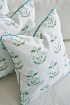 two pillows sitting on top of a couch next to each other with green plants printed on them