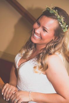 a woman in a white dress is smiling and holding a wooden stick with flowers on it