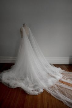 the back of a white wedding dress on a mannequin stand in front of a wall