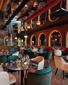 the interior of a restaurant with tables, chairs and chandeliers hanging from the ceiling