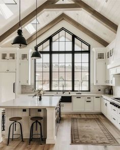 a large kitchen with white cabinets and black accents on the ceiling, along with an area rug that matches the hardwood flooring