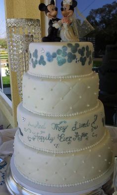 a wedding cake with mickey and minnie mouse figurines sitting on top of it