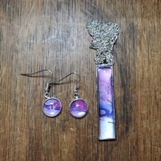 a pair of earrings and pendants on top of a wooden table next to a piece of jewelry