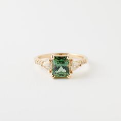 a green and white diamond ring on a white background