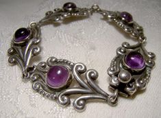 A Mexican sterling silver and amethyst cabochons bracelet circa 1930s 1940 This 7-3/8" x 5/8" wide bracelet is a classic Mexico design, and the 5 cabochon amethysts are genuine. This bracelet is stamped STERLING 925 TAXCO with a 3 in the eagle mark for Taxco. It weighs 18.2 grams and has a box clasp, and it is in excellent vintage condition with no  corrosion, losses, damage or repairs, but there is a small triangle shape gap on one amethyst. It does not appear to be damage, but an original aspect of the stone.    Jewelry will have signs of use. Expedited tracked parcel to the U.S. starts at $23.00 and expedited parcel within Canada starts at $17.00 (tracking and loss insurance is included).  At this time, we are required to choose a single postal rate, which may not be applicable to your Vintage Sterling Silver Bracelet With Gemstone, Modernist Silver Jewelry With Cabochon, Classic Amethyst Cabochon Jewelry, Vintage Polished Cabochons For Formal Use, Vintage Purple Metal Bracelets, Vintage Silver Gemstone Bracelets, Vintage Silver Bracelets With Gemstones, Vintage Silver Amethyst Bracelets, Vintage Amethyst Cabochon Jewelry