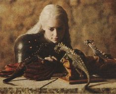 a woman with long white hair holding a dragon in her hand while sitting on a chair