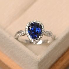 an engagement ring with a blue heart shaped sapphire surrounded by white diamonds in a box