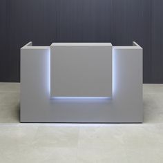 a white reception table sitting on top of a tiled floor next to a black wall