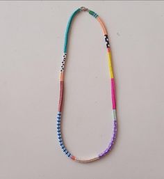 a multicolored beaded necklace on a white surface