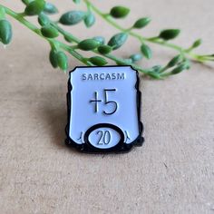 a close up of a badge on a table with flowers in the background and text that reads sarcasm