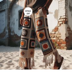 a woman standing in the sand wearing crocheted pants with fringes on them