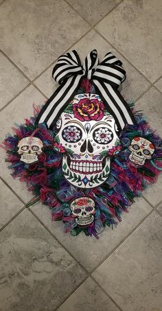 a wreath decorated with sugar skulls and ribbons on the floor in front of a tiled floor