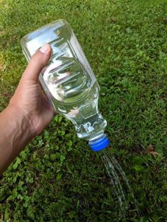 a hand is holding a water bottle in the grass