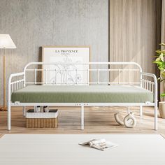 a white metal daybed sitting on top of a hard wood floor next to a potted plant