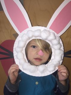 a little boy holding up a paper plate with bunny ears on it's face