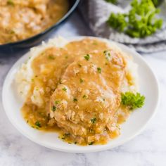 meatballs covered in gravy on a plate with mashed potatoes and parsley