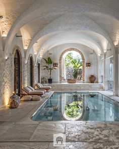 an indoor swimming pool in the middle of a room with stone walls and arched doorways