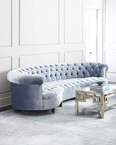 a blue couch sitting next to a table on top of a white carpeted floor