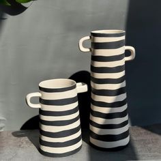 two black and white striped vases sitting next to each other on top of a table