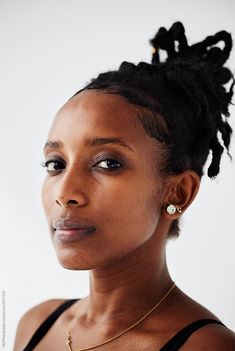 a woman with braids on her hair looking off to the side while wearing a black tank top