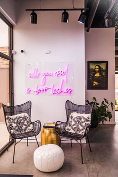 two chairs and a table in front of a neon sign that says all you need is love