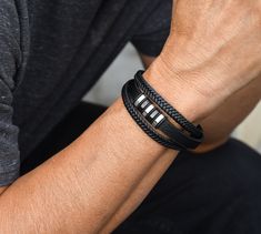 "~Quality, triple black leather bracelet with stainless steel details and magnetic clasp. ~Standard/medium men size - 8.25\". ~Metal components are stainless steel: Water, heat & Sweat resistant. No discolouration or tarnishing (no green skin). Hypoallergenic. Your item will arrive in a drawstring pouch - Ready for Gift Giving! *The beaded set of bracelets shown on the model is available separately here: https://www.etsy.com/ca/listing/1284186308/men-bracelet-set-black-lava-beads?click_key=c6a052c070ae1c848146ecaca7bce276ceaf69ec%3A1284186308&click_sum=3f291ddc&ref=shop_home_active_21&pro=1" Black Magnetic Leather Bracelet As Gift, Magnetic Black Leather Bracelet Gift, Black Leather Magnetic Bracelet As A Gift, Minimalist Black Braided Bracelet With Stainless Steel Clasp, Black Leather Magnetic Bracelet Gift, Black Minimalist Braided Stainless Steel Bracelets, Minimalist Black Stainless Steel Braided Bracelets, Mens Bracelet Black, Beaded Leather Bracelet