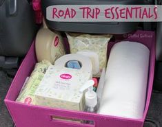 a pink trunk filled with baby items in the back of a car, and road trip essentials written on it