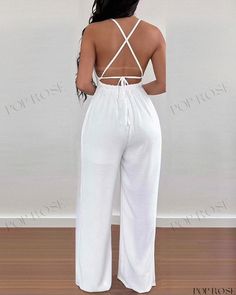 the back of a woman in white jumpsuits standing on a wooden floor with her hands behind her back