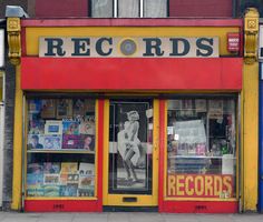 an old record store with records on the front and yellow trim around the window display