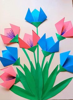 the paper flowers are arranged on top of each other, and have green stems in them