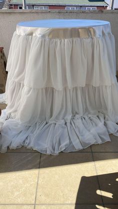 a white table with ruffles on it sitting in front of a balcony overlooking the ocean