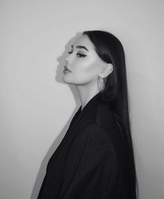 a black and white photo of a woman with long dark hair wearing large hoop earrings