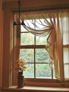 a vase with flowers sitting on a window sill next to a curtained window