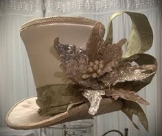 "This stunning gold and green tree topper top hat and/or centerpiece is READY TO SHIP. This top hat can be used as an elegant Christmas tree Topper or a Christmas decoration centerpiece. Made with ivory canvas fabric and decorated in ivory and gold.    Measures about 9.5\" tall (not including the picks) x 12\" at the brim Our top hat tree toppers/centerpieces are 100% handmade by us with high-quality materials. The designs are our own unique design. Our top hat tree toppers/centerpieces stand al Top Hat Christmas Tree Topper, Hat Christmas Tree Topper, Top Hat Christmas Tree, Christmas Top Hat, Top Hat Centerpieces, Top Hat Tree Topper, Silver Tree Topper, Gold Tree Topper, Peacock Christmas Tree