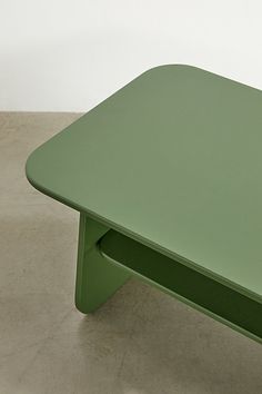 a green coffee table sitting on top of a cement floor next to a white wall