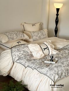 a bed with white sheets and pillows on it next to a black lamp in the corner