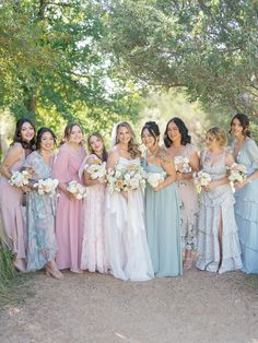 a group of women standing next to each other wearing dresses and holding bouquets in their hands