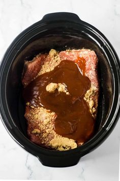 a slow cooker filled with meat and sauce