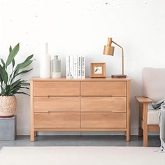 a living room with a couch, chair and wooden dresser next to a potted plant