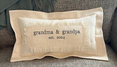 an embroidered pillow with the words grandma and grandpa on it sitting on a couch next to pillows