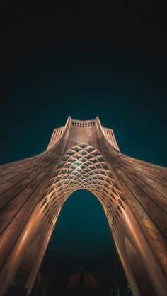 the top of a tall building with lights on it's sides and an arch in the middle