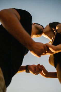 a man and woman kissing each other while standing next to each other with their hands together